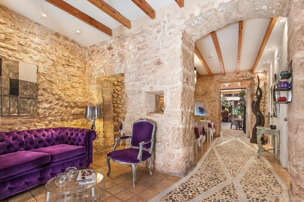 a living room with a purple couch and a stone wall at Ca´n Pere in Alcudia