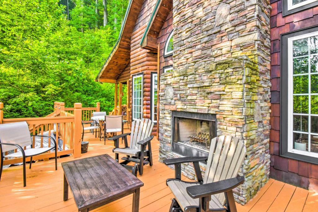a deck with chairs and a stone fireplace at Serene Smoky Mountains Cabin Near Chatuge Lake in Hayesville