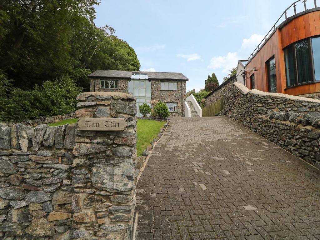 una pared de piedra con una señal frente a un edificio en Tan Twr en Llanfairpwllgwyngyll