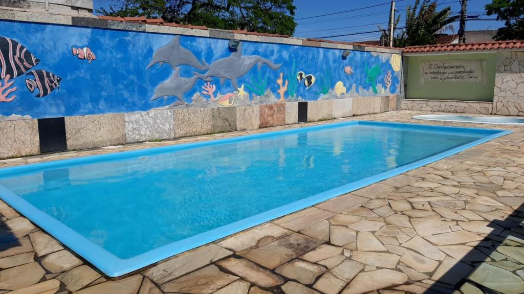 a swimming pool with dolphins painted on a wall at Pousada Campo Verde in Guarapari
