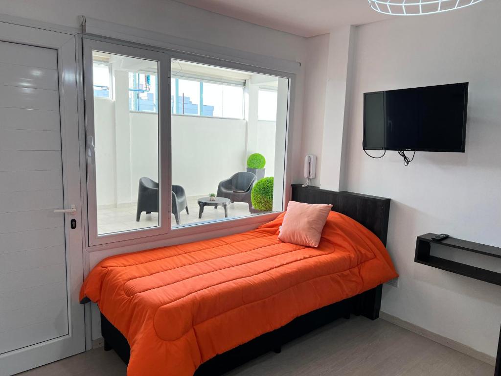 una camera da letto con un letto con una coperta arancione e una finestra di APART trelew 3 a Trelew