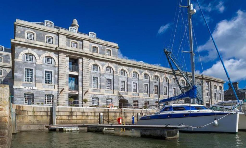 um barco está ancorado em frente a um grande edifício em Royal William Yard - Lovely 1-Bed Apartment in Historic Plymouth em Plymouth