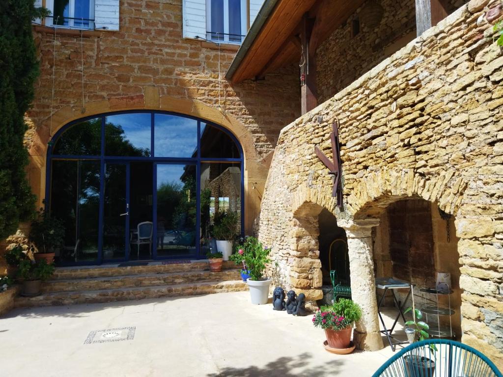 a stone building with two arches and a patio at La ferme du vincent in Liergues