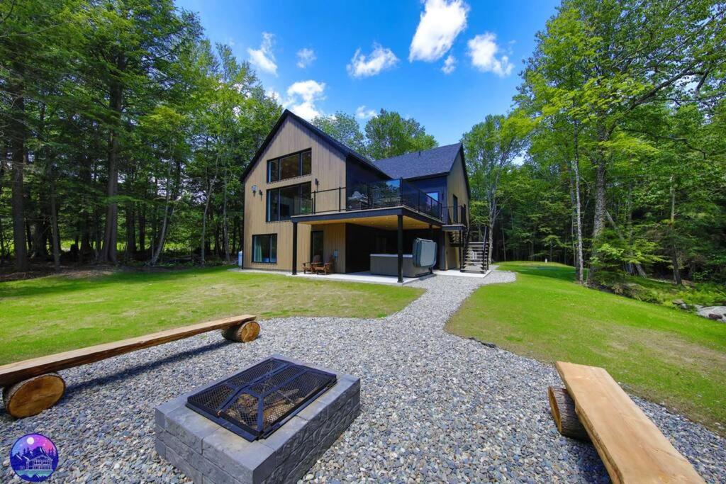 une maison avec un foyer extérieur en face de celle-ci dans l'établissement Chalet Forestria - SPA- Billard- Ski, à Mansonville