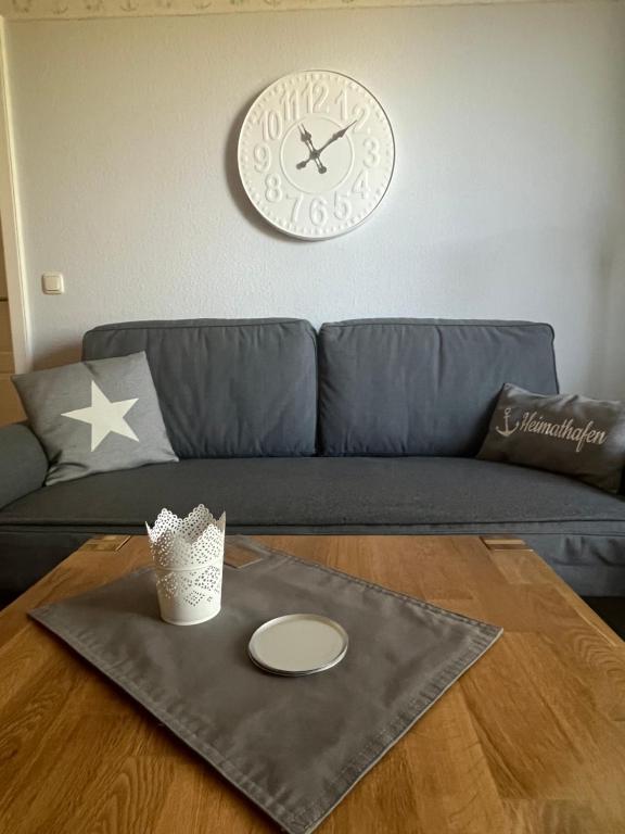 uma sala de estar com um sofá, um relógio e uma mesa em Nordlicht in Büsum-Stinteck em Stinteck