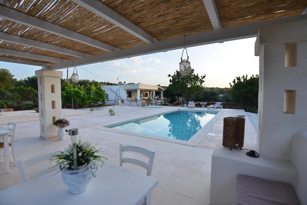 a patio with a pool and a table and chairs at Villa del Sole in Ostuni