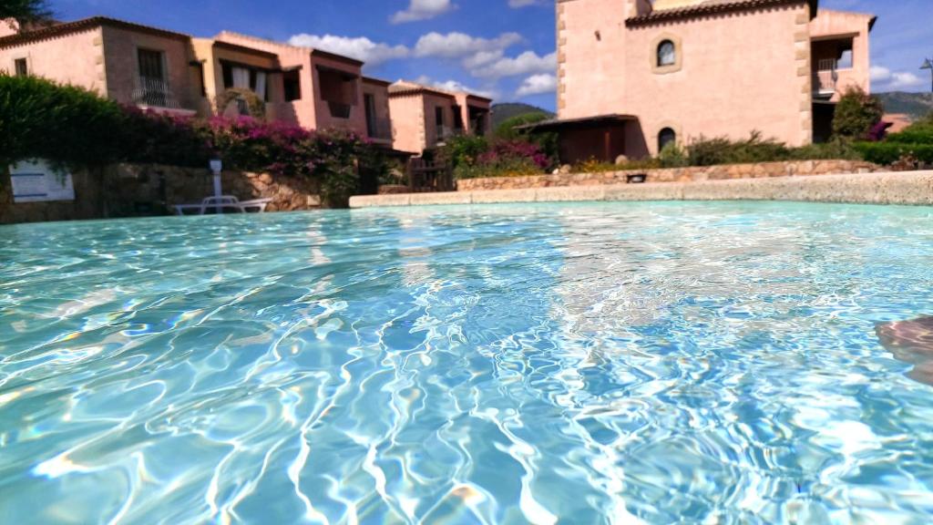 uma piscina com água azul em frente a uma casa em Fiordaliso Sweet Home em Olbia