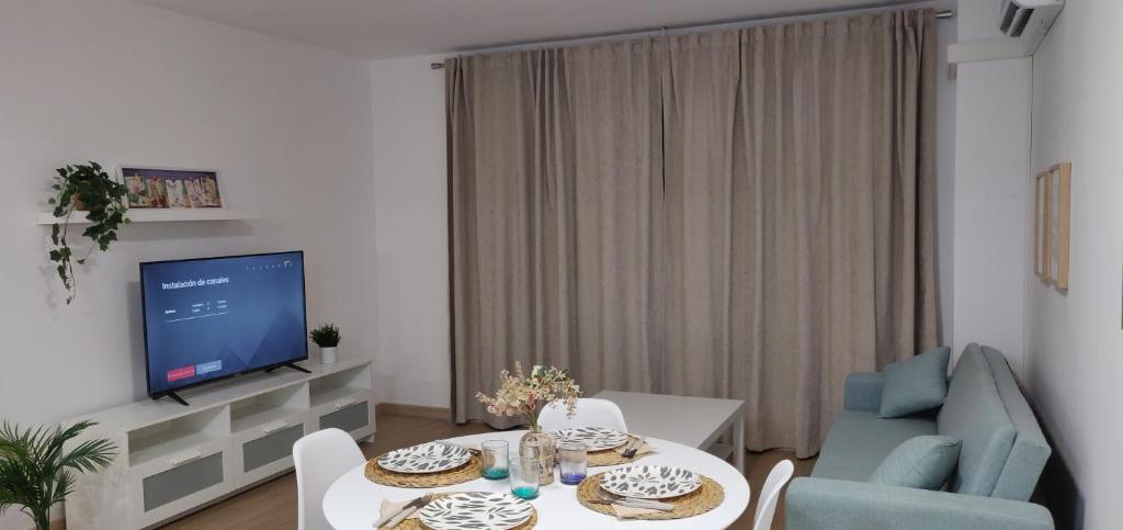 sala de estar con TV, mesa y sillas en Apartamento en Canet Playa con Parking y WIFI, en Canet de Berenguer