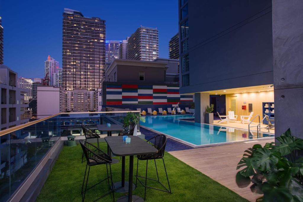 um pátio no último piso com uma mesa e cadeiras e uma piscina em Atwell Suites - Miami Brickell, an IHG Hotel em Miami