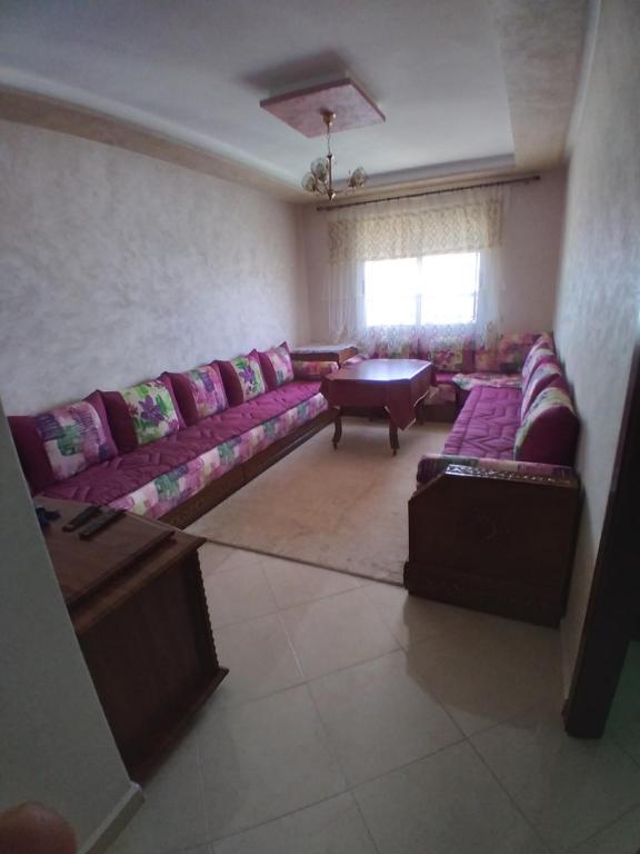 een woonkamer met een paarse bank en een tafel bij Résidence Ghita 2 in Martil