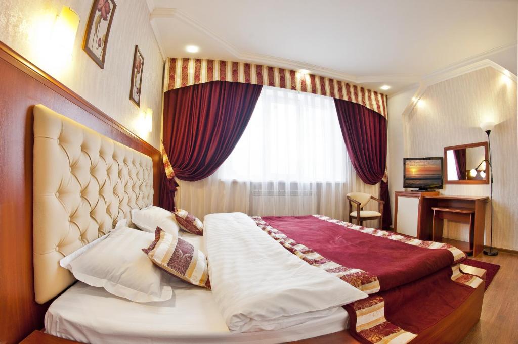 a bedroom with a large bed with a large window at Aureliu Hotel in Krasnodar