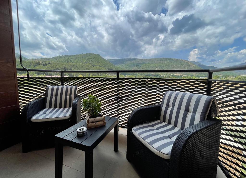 two chairs and a table on a balcony with a view at APARTAMENTOS RioMonte 2 - DeLuxe in Boltaña