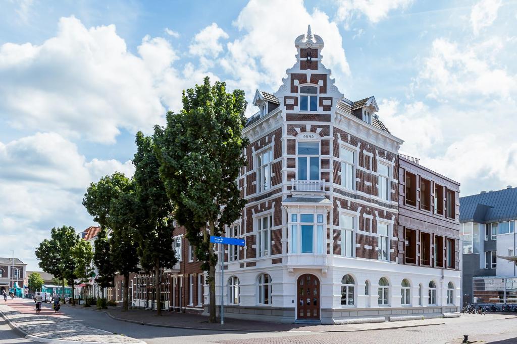 een hoog wit gebouw met een toren op een straat bij Eclectic Hotel Copper in Middelburg