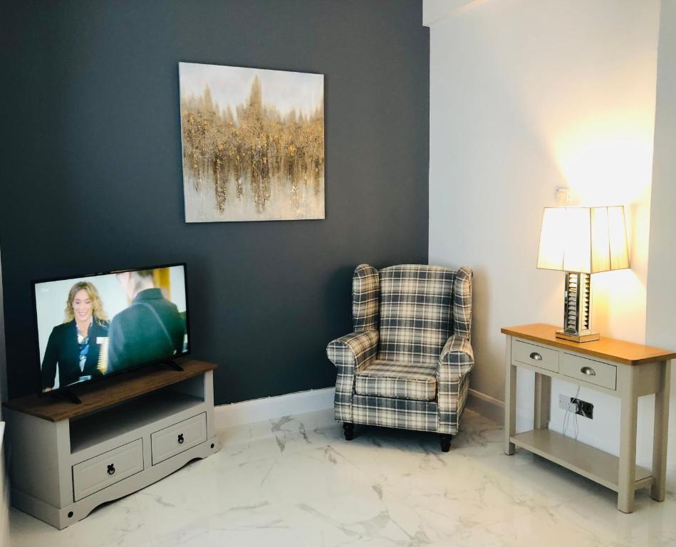 a living room with a tv and a chair at Ballycastle Town Centre Studio Apartment in Ballycastle