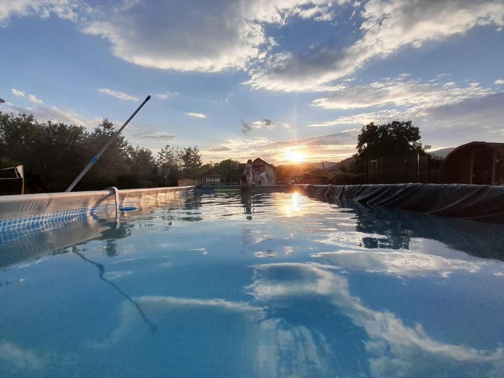 una piscina con il tramonto sullo sfondo di Pensiunea Valea Șușiței, Ciubar, Sauna, ATV, Safarii Jepp Offroad Ghid Turistic, Climbing, Rafting, Paragliding a Târgu Jiu
