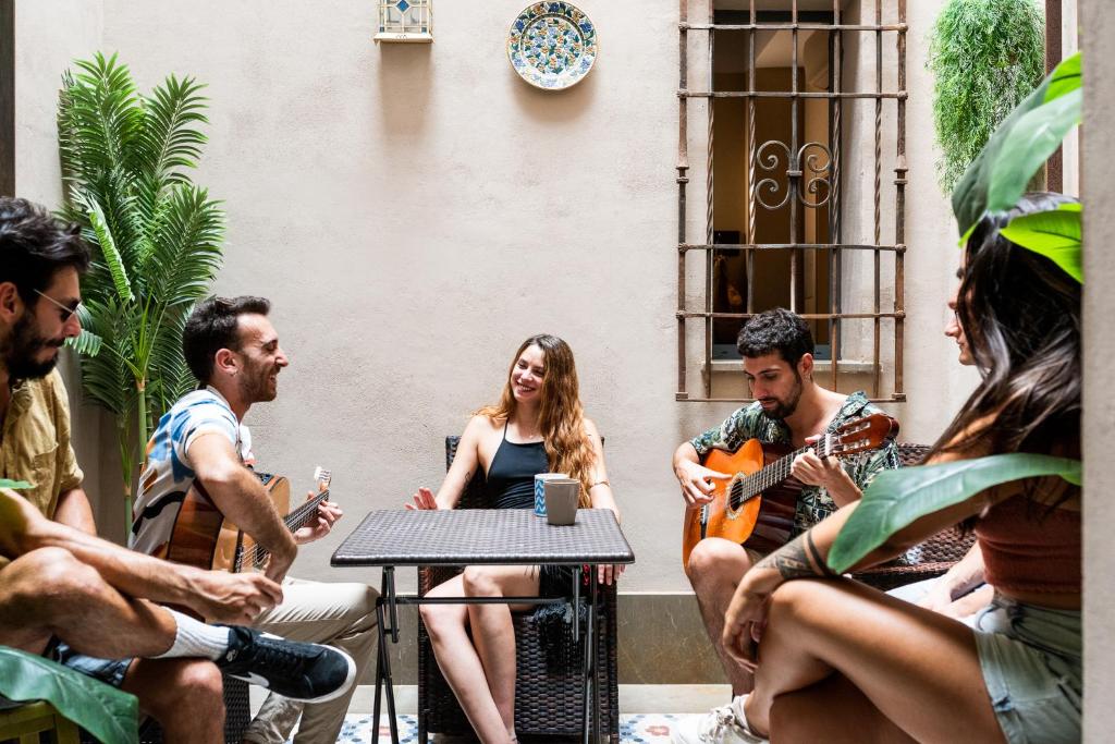 um grupo de pessoas sentadas em torno de uma mesa tocando música em Hostel Carlota Braun em Granada