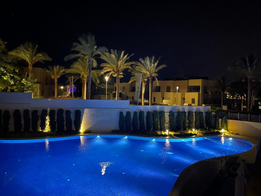 uma piscina à noite com palmeiras e edifícios em Al Raha Village - Aqaba em Aqaba