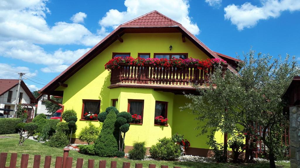 Casa amarilla con balcón con flores rojas en Apartmán Adrianka, en Turčianske Teplice