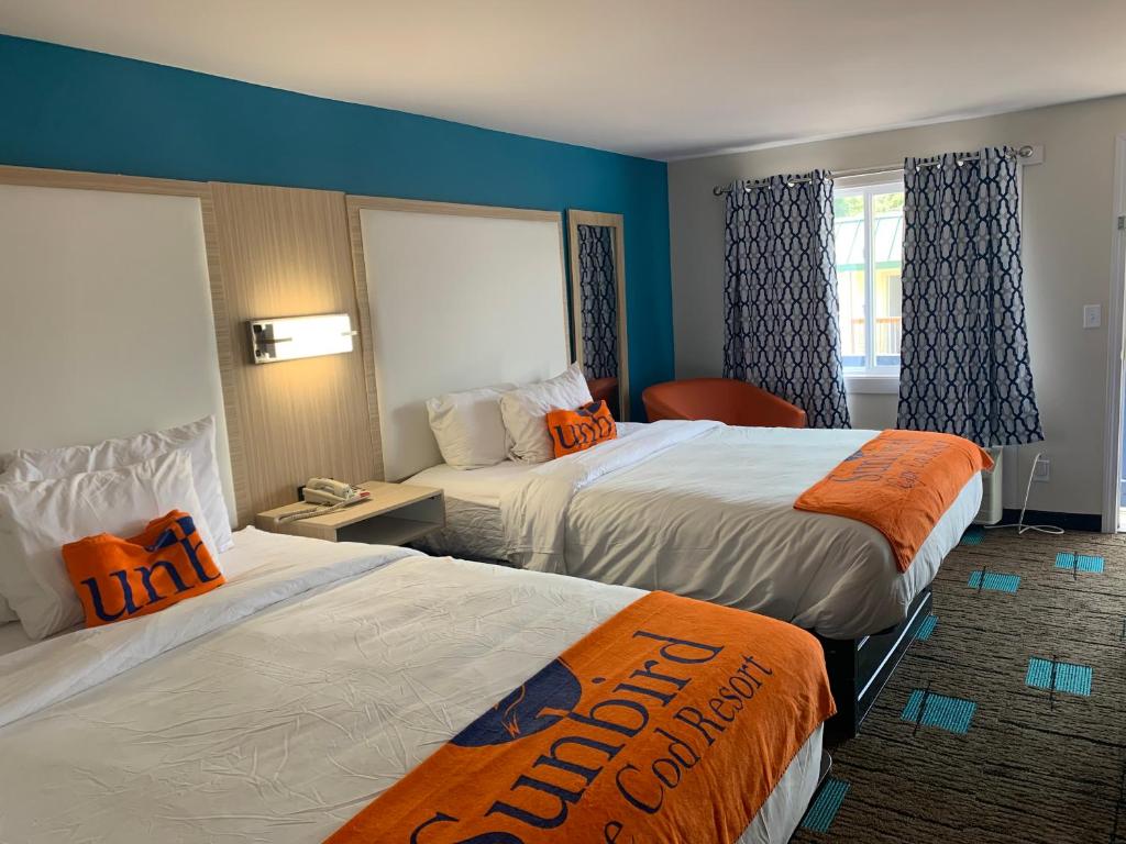 Cette chambre d'hôtel comprend 2 lits avec des oreillers orange. dans l'établissement Sunbird Cape Cod Annex, à West Yarmouth