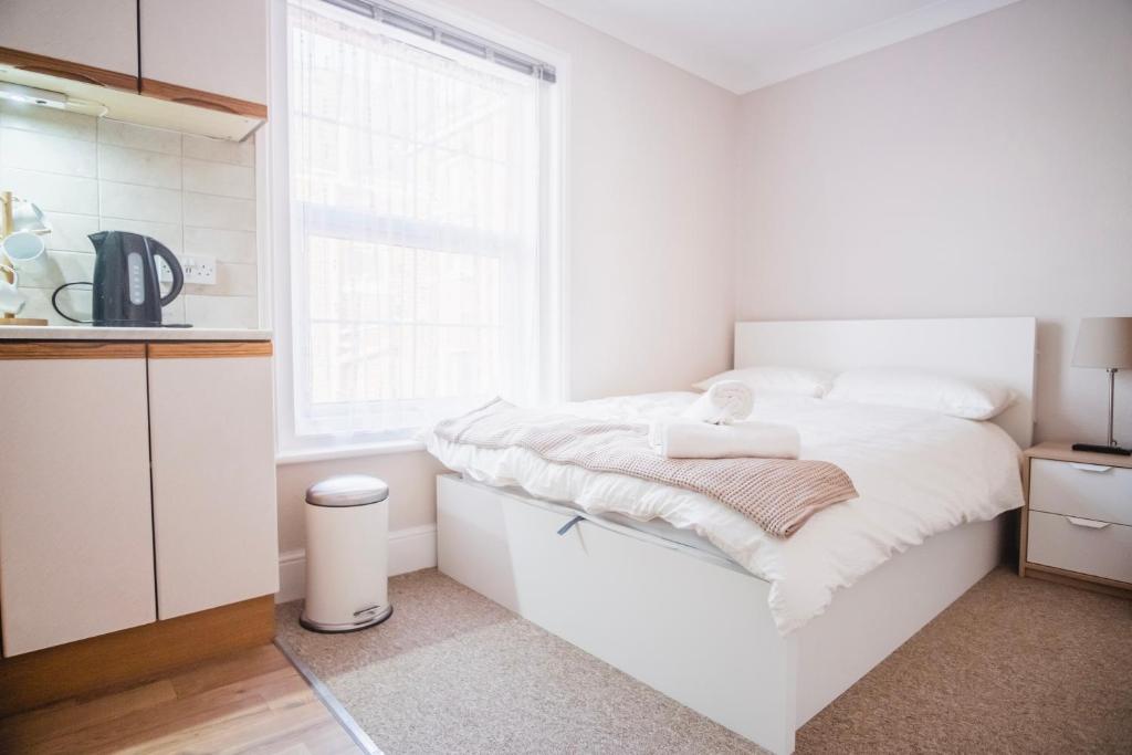 a white bedroom with a bed and a window at Poole Stay in Poole