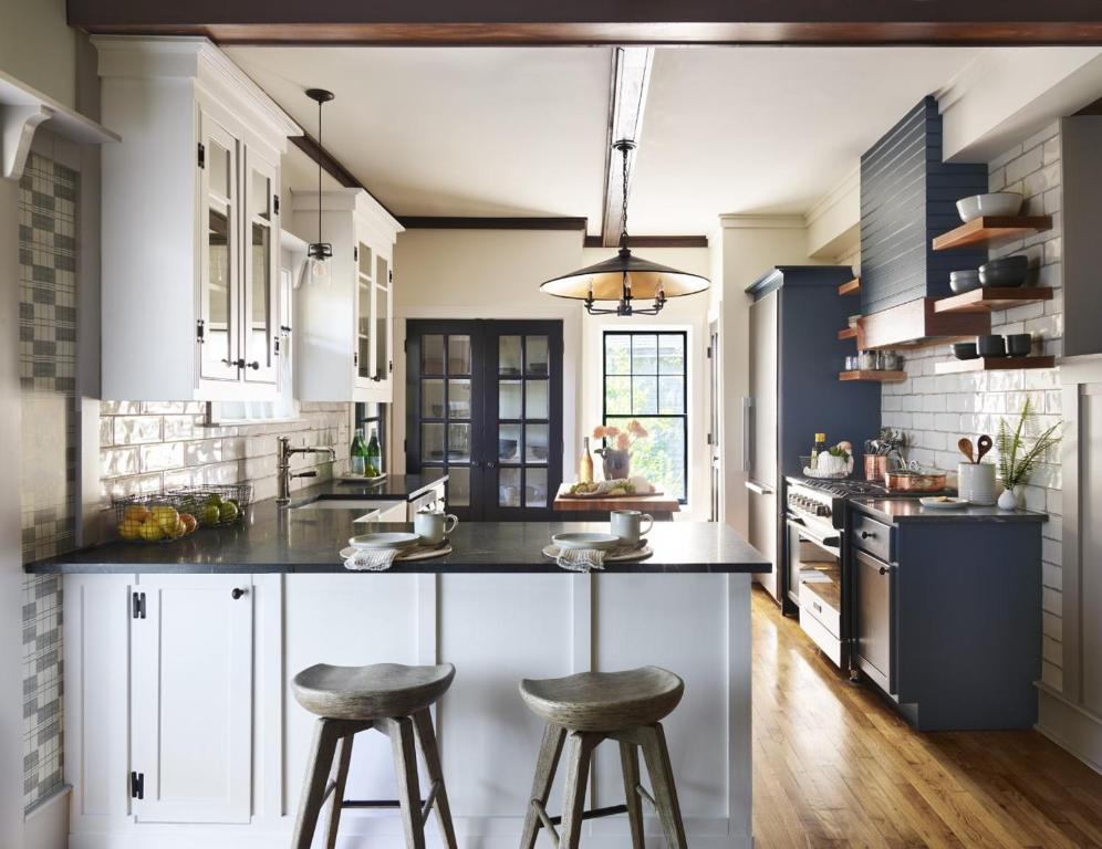 a kitchen with white cabinets and bar stools at 52 Union in Nantucket