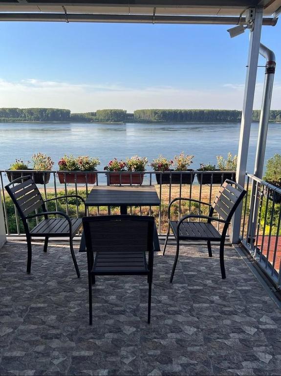 a patio with two chairs and a table with a view of the water at Къща за гости Ненийски in Lom