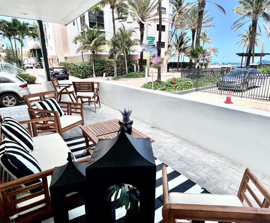 a patio with a table and chairs and palm trees at The Pearl Beachside Apartments on Hollywood Beach in Hollywood
