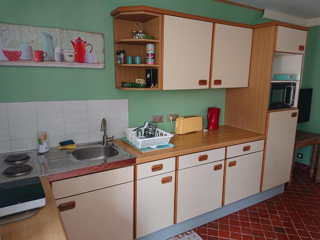 une cuisine avec des armoires blanches et un évier dans l'établissement L'appart, à Grandcamp-Maisy