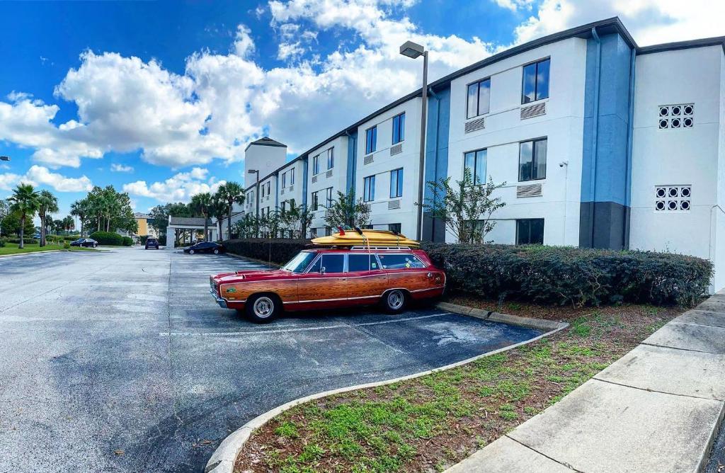 un coche aparcado en un aparcamiento al lado de un edificio en Destiny Palms Hotel Maingate West en Kissimmee