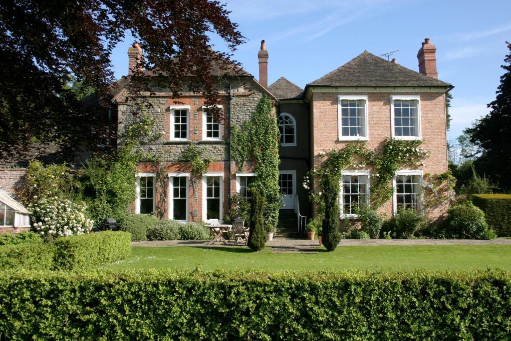 uma casa velha com uma sebe verde em frente em The Old Vicarage em Kington