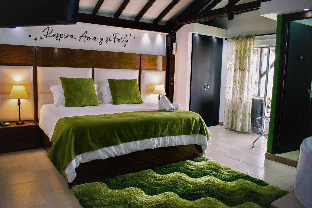 a bedroom with a large bed with a green blanket at Hotel Jade Spa in Santa Rosa de Cabal