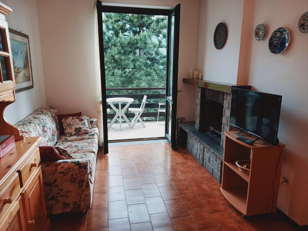 een woonkamer met een bank, een tv en een open haard bij Appartamento incantevole a Sestola in Sestola