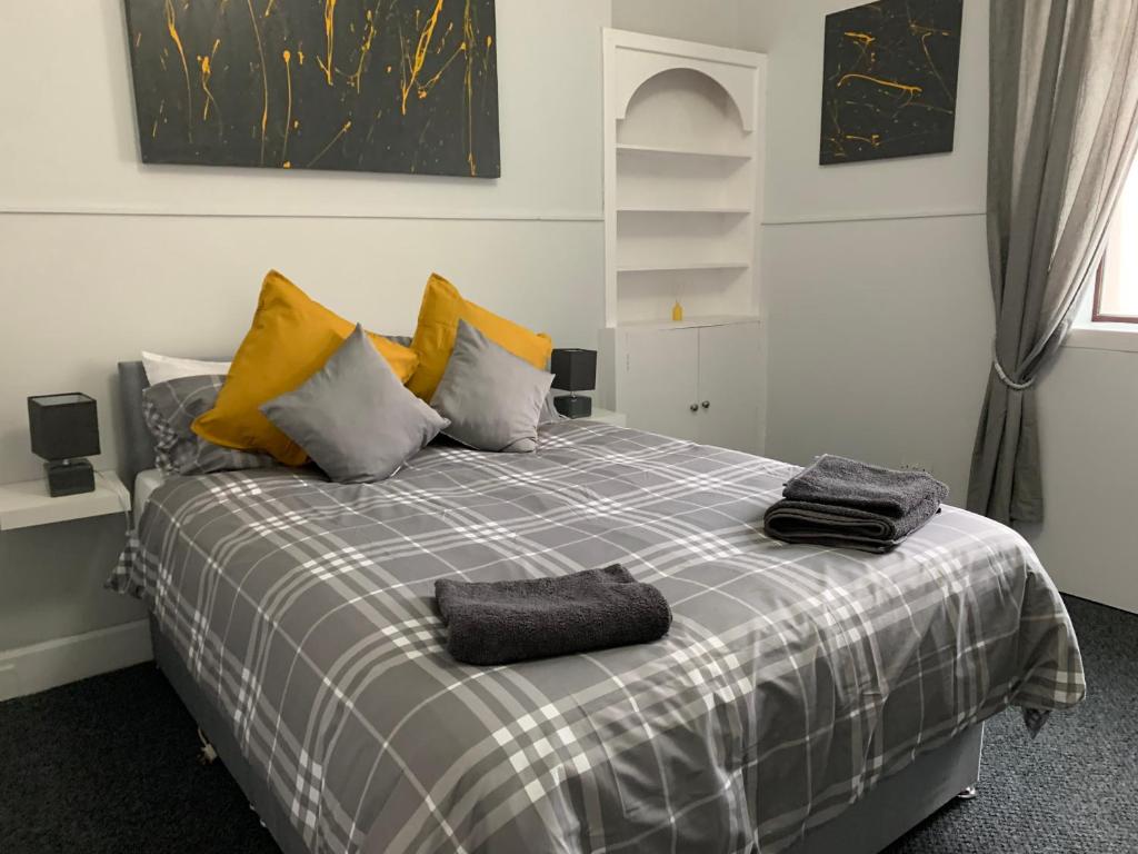 a bedroom with a bed with yellow and gray pillows at Nelson st (VIEWPARK) in Largs