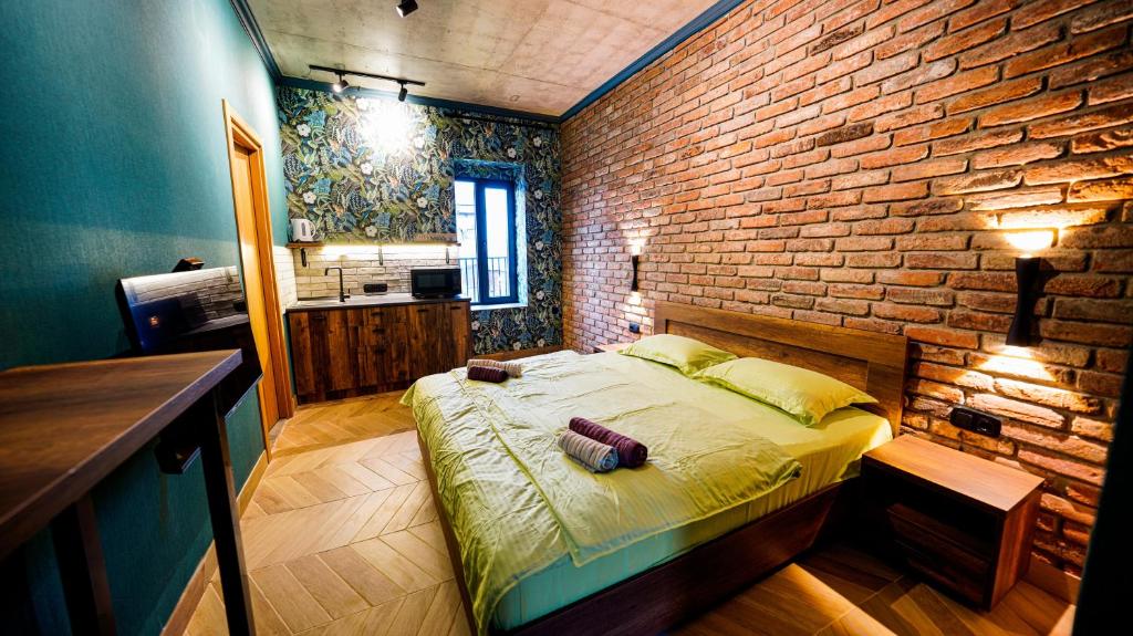 a bedroom with a bed and a brick wall at Anbani Apartments - City Center in Tbilisi City