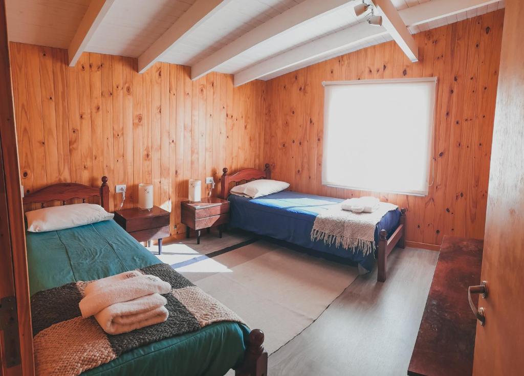 a bedroom with two beds in a room with wooden walls at CABAÑA LA SUREÑA in San Martín de los Andes