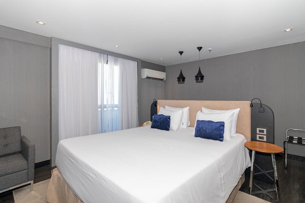 a bedroom with a large white bed with blue pillows at Suite Particular Brasília in Brasilia