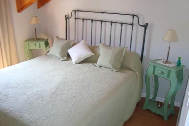 - une chambre avec un lit avec des oreillers et 2 tables dans l'établissement Roca, à San Martín de los Andes