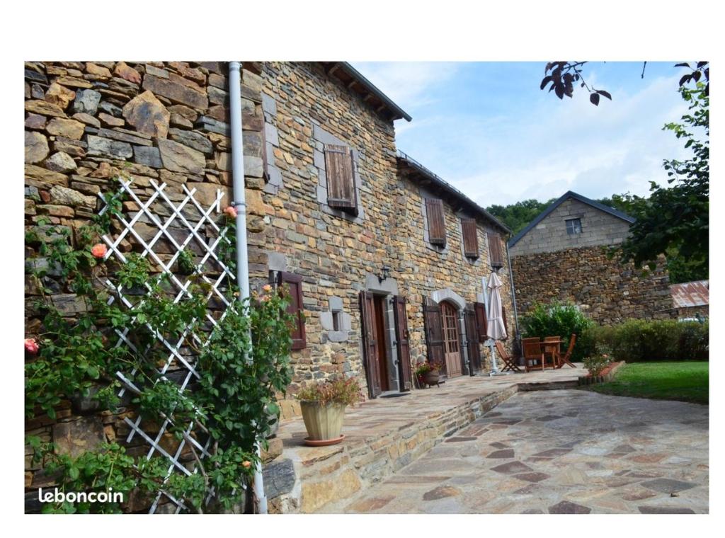 ein Steinhaus mit einem Zaun und einer Terrasse in der Unterkunft Maison Encantalou 