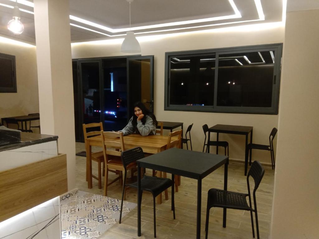 French Apartment With restaurant في Taourirt: امرأة تجلس على طاولة في مطعم