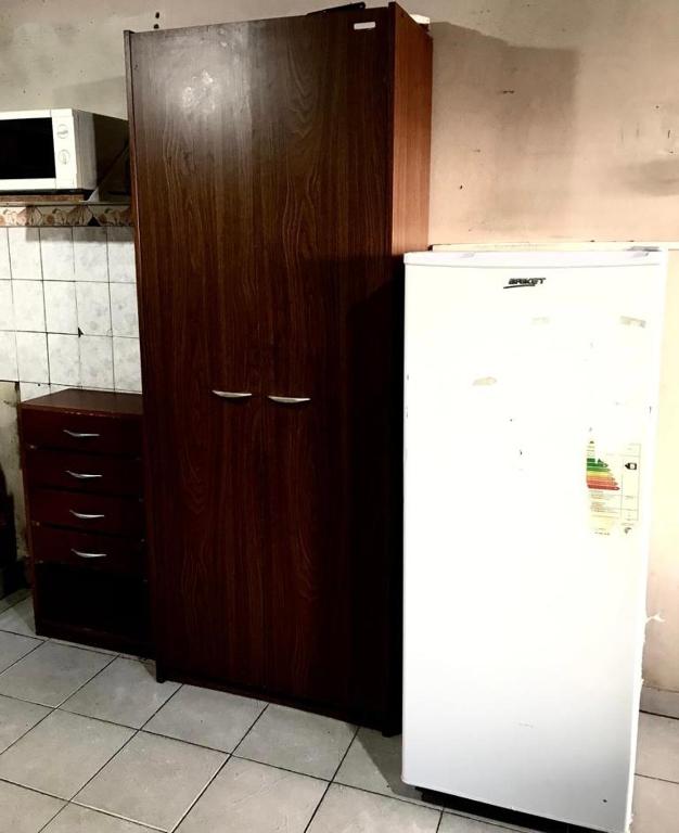 Una cocina con un armario de madera al lado de un refrigerador. en Departamentos Sarmiento, en San Luis