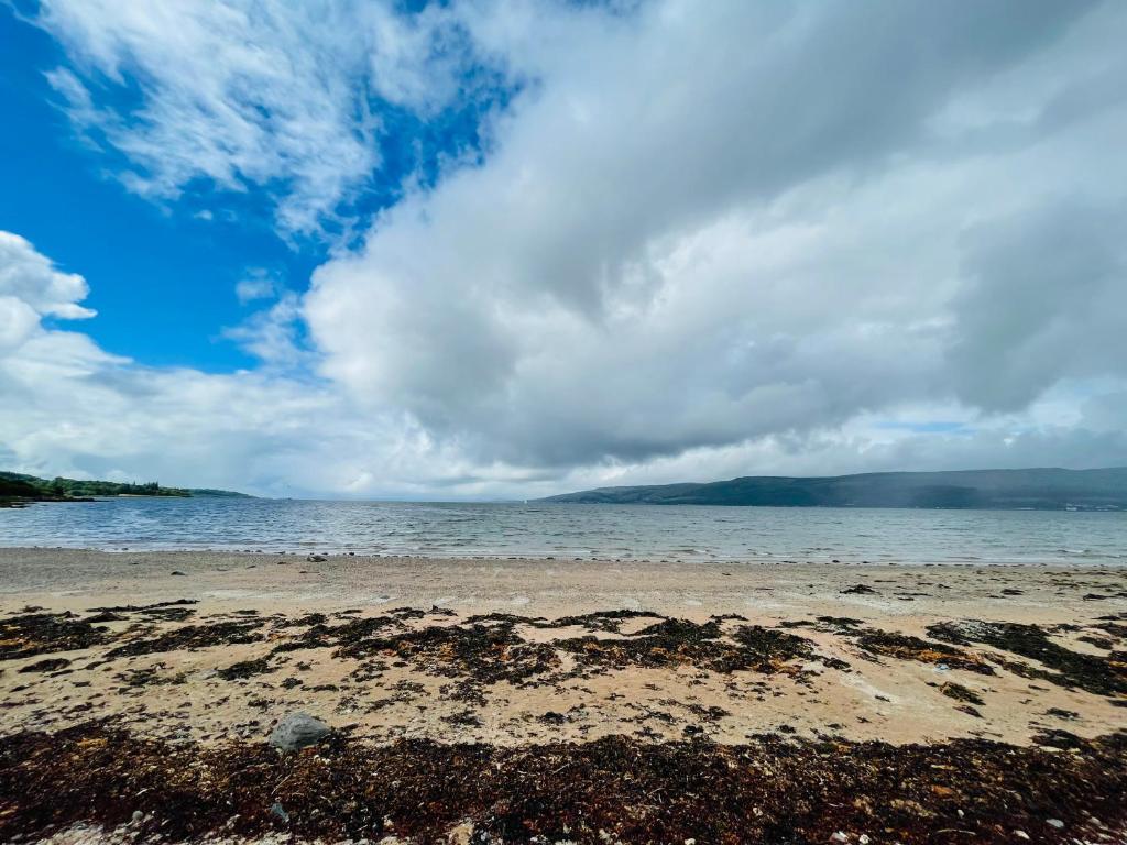 a beach with a cloudy sky and the water at A Shore Stay in Gourock
