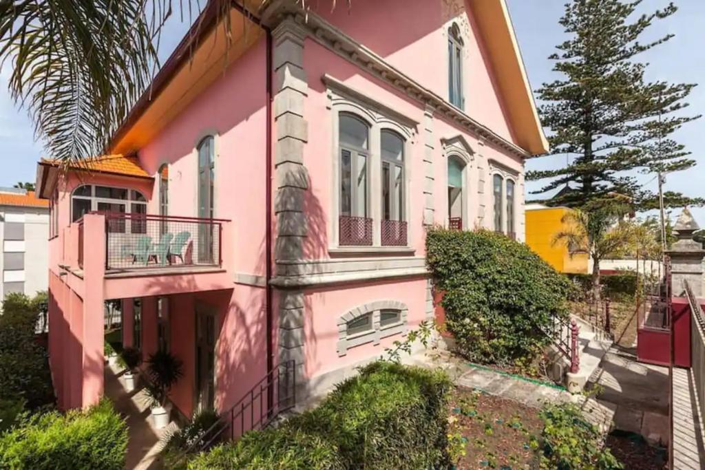 uma casa cor-de-rosa com uma varanda em Moledo - Listening the Waves em Moledo