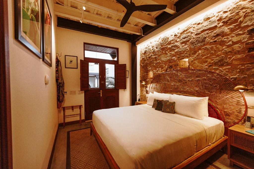 a bedroom with a large bed and a stone wall at Amarla Boutique Hotel Casco Viejo in Panama City