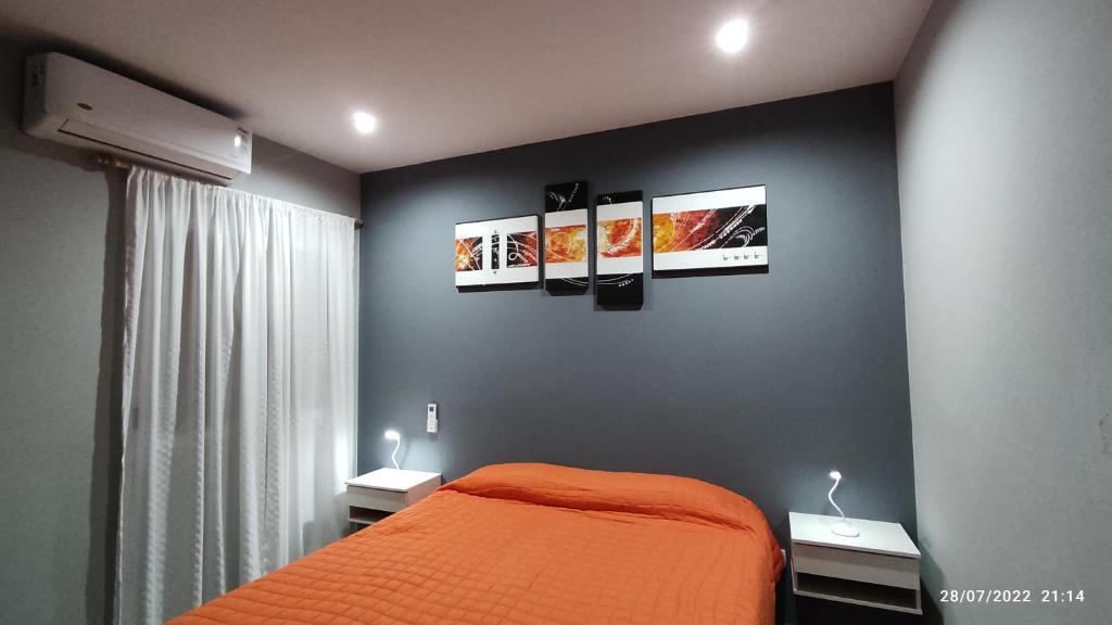 1 dormitorio con 1 cama naranja y 3 cuadros en la pared en Departamento Norte Pueyrredon en Santa Lucía