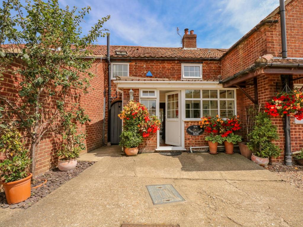 a brick house with potted plants in front of it at Holly Cottage in Swaffham