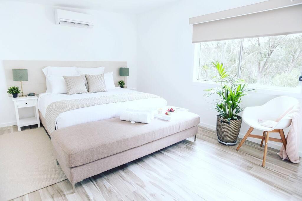 a white bedroom with a bed and a chair at Hickey Vale Farm Lodge Pet Friendly in Broadford