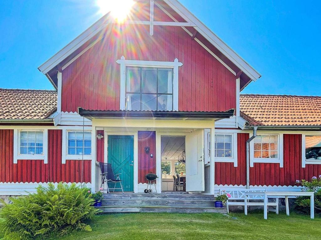 una casa roja y blanca con un banco delante en Holiday home ELLÖS IX en Ellös