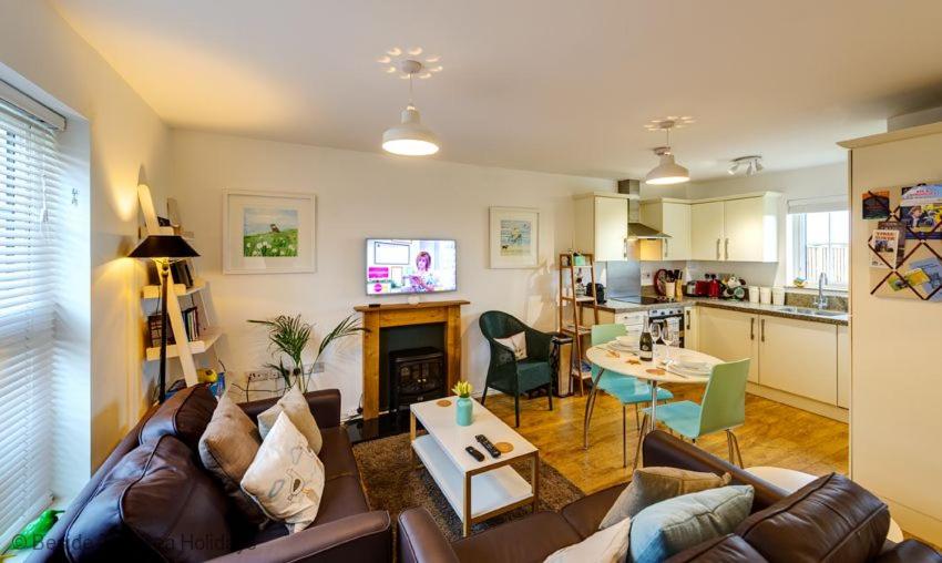 ein Wohnzimmer mit einem Sofa und einem Tisch sowie eine Küche in der Unterkunft Mallow Cottage in Camber