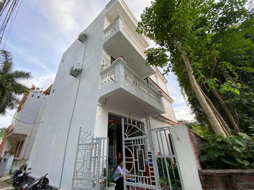 a woman standing outside of a white building at HT Homestay CAT BA in Cat Ba