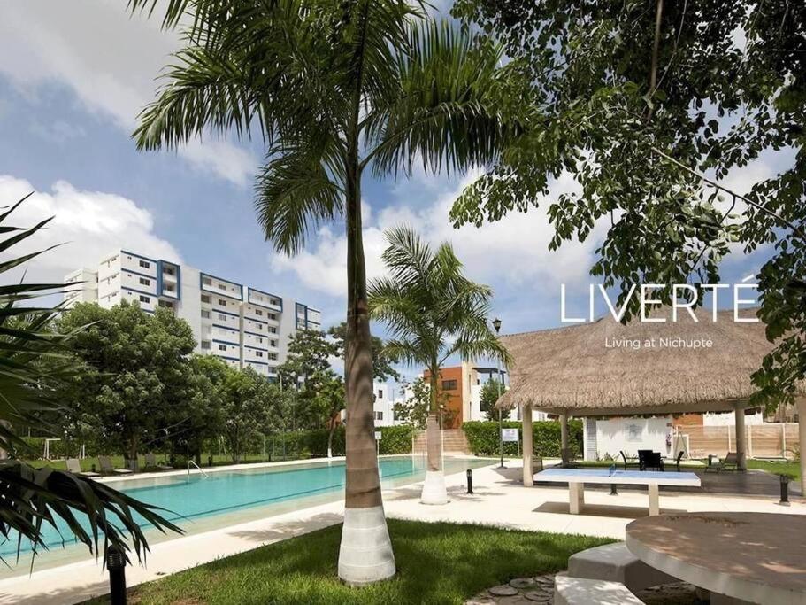 a resort with a swimming pool and a palm tree at Apartamento exclusivo piscina, jaccuzi, céntrico. in Cancún